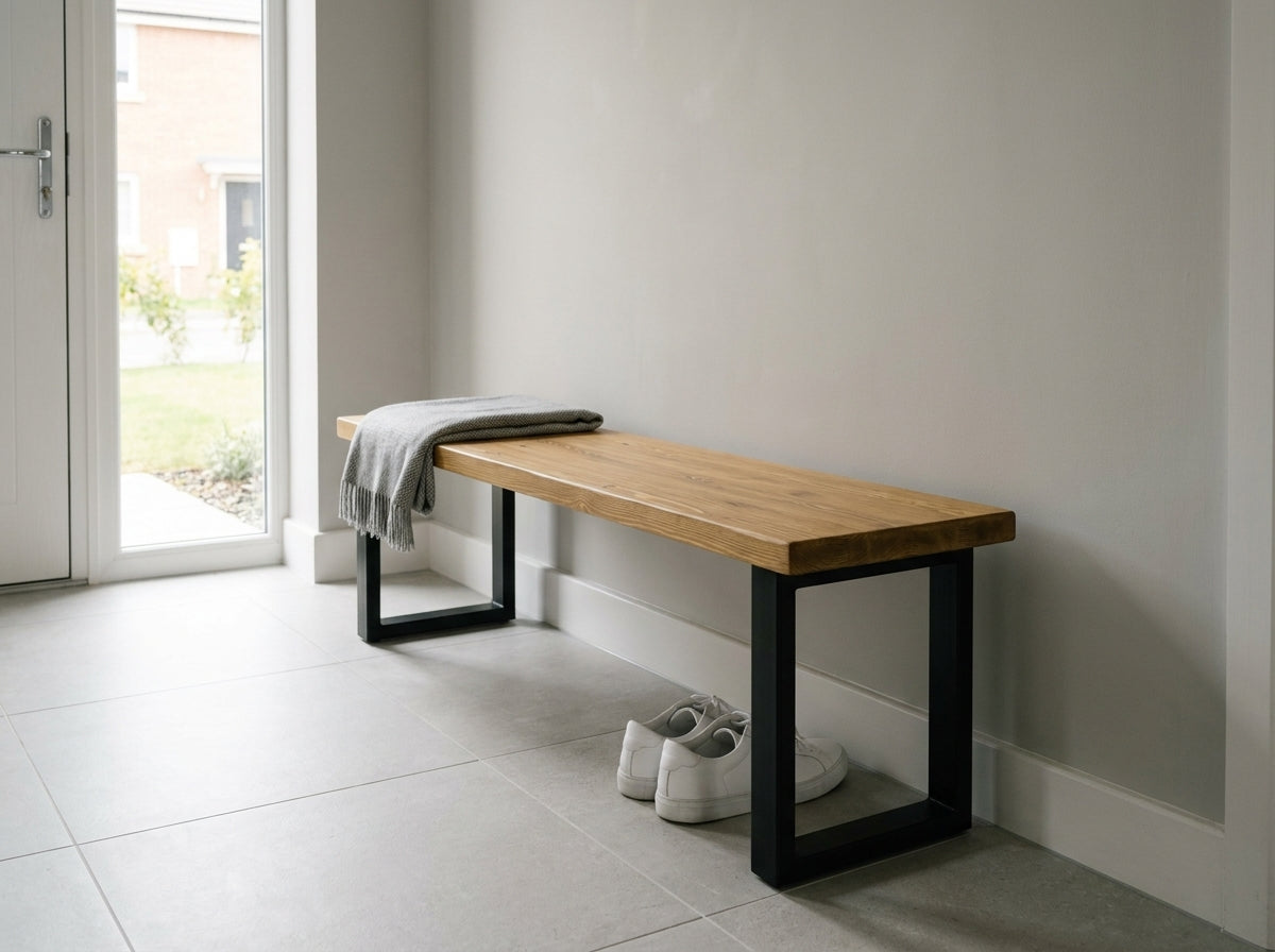 Wooden bench with black metal legs against a white wall in a bright room.